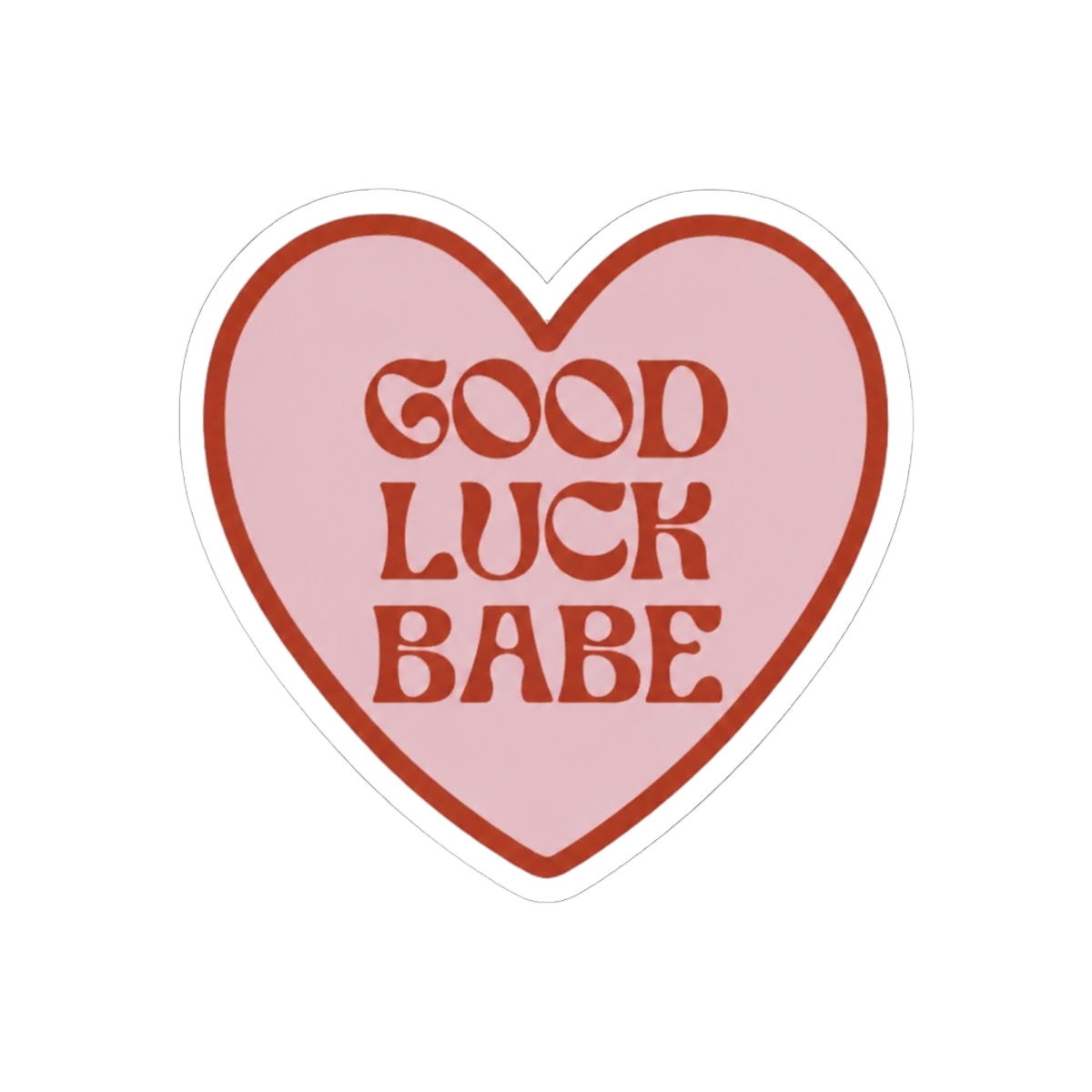 A heart-shaped sticker with a pink interior and a dark red border. The sticker features the words "GOOD LUCK BABE" in dark red, retro-style lettering. The sticker is held between two fingers against a...